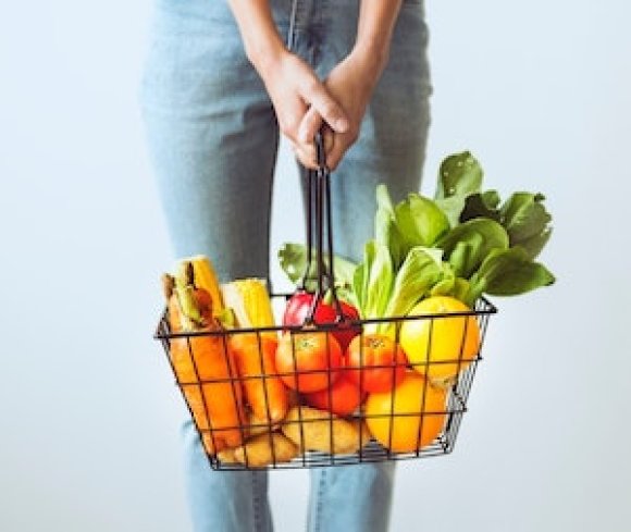 woman holding basket of fruits and vegetables